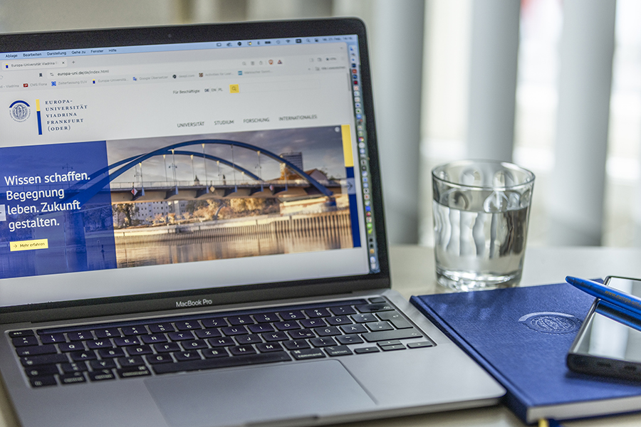 Bild des Laptops, Stift, Wasserglas, Notizbuch und Handy